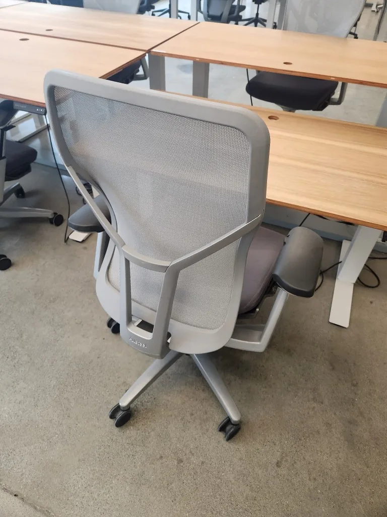 Rear view of a task chair at wood-top height-adjustable desks