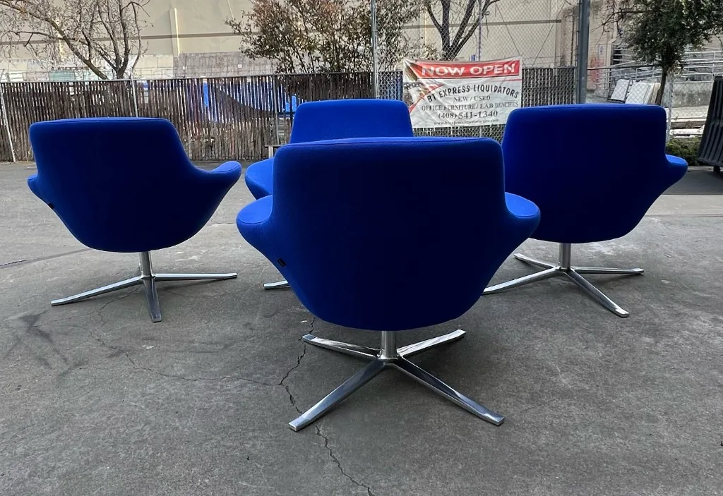 Set of four blue upholstered swivel lounge chairs with polished bases