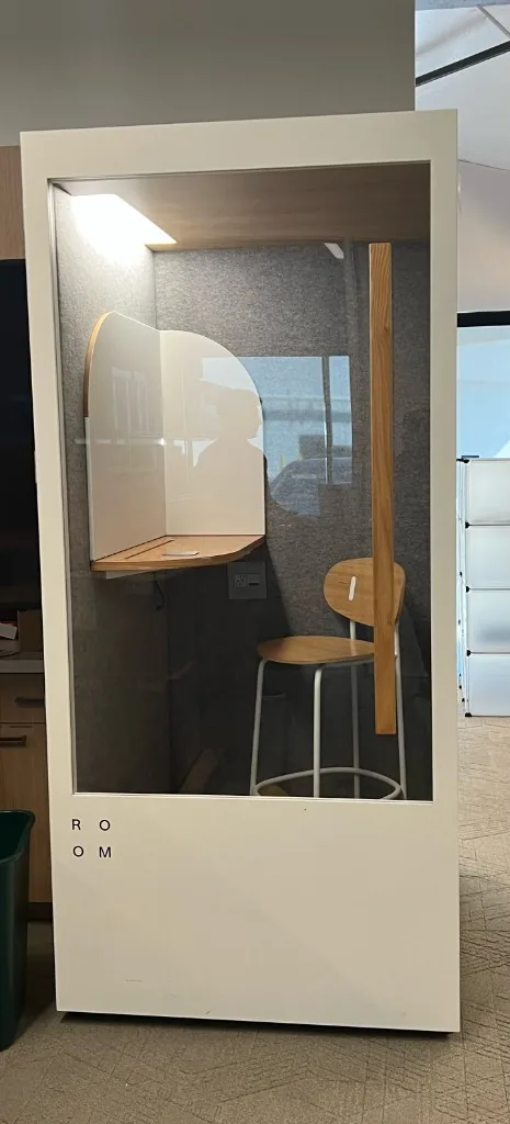 Single-person office phone booth with desk shelf and stool